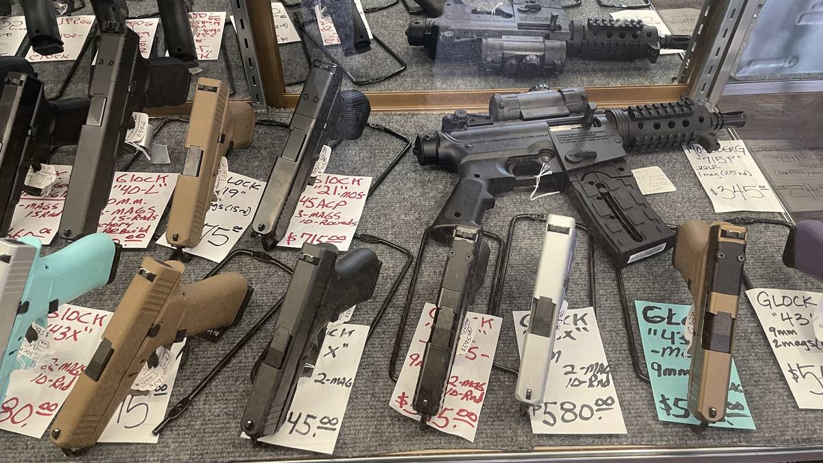 Mixed handgun and rifle display: Glock 40-L 10mm, Glock 19, Glock 21 MOS .45 ACP, two-tone Glock 43X, FDE Glock 43, and a Mossberg 715P .22LR with optic.