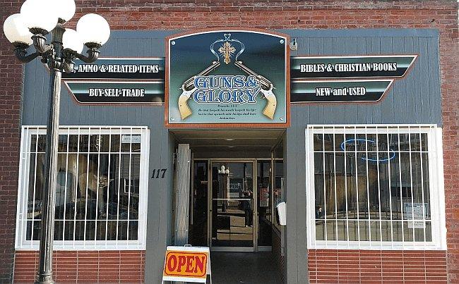 Guns and Glory storefront — a refurbished historic building at 117 E Center St in downtown Le Roy, Illinois, with a painted sign showing 'Guns, Ammo & Related Items / Buy-Sell-Trade' and 'Bibles & Christian Books / New and Used'.